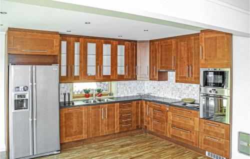 une cuisine avec des placards en bois et des appareils en acier inoxydable dans l'établissement Awesome Home In Hagavik With House Sea View, à Hagavik