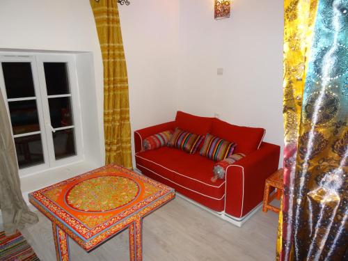 a living room with a red couch and a table at La Fontenelle Chambres d'Hôtes in Sainte-Sévère