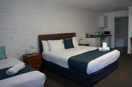 a bedroom with two beds and a brick wall at Waves Motel and Apartments in Warrnambool