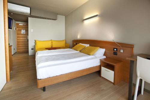 a bedroom with a large bed with yellow pillows at Ambienthotel Spiaggia in Malcesine