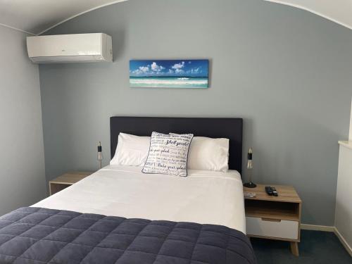 a bedroom with a large bed and a night stand at Academy Motor Inn in Tauranga