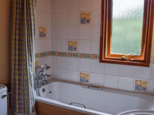 y baño con bañera y ventana. en Teasel Lodge - Uk39647, en Lunga