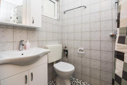 biała łazienka z toaletą i umywalką w obiekcie Apartments Skundric w mieście Vir