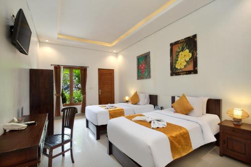 Habitación de hotel con 2 camas y escritorio en Hotel Arsa Santhi Nusa Penida en Nusa Penida