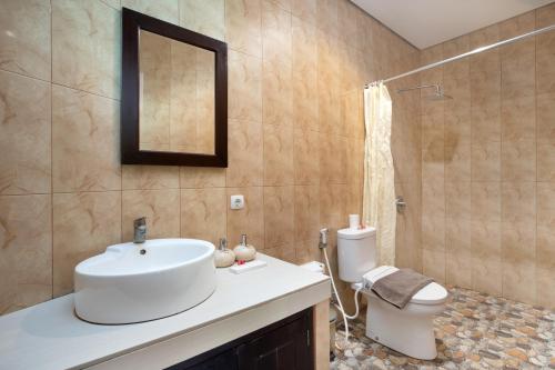 a bathroom with a sink and a toilet and a mirror at Hotel Arsa Santhi Nusa Penida in Nusa Penida