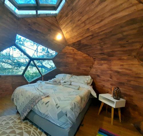 Magno Glamping في Boyacá: غرفة نوم بسرير في غرفة بجدران خشبية
