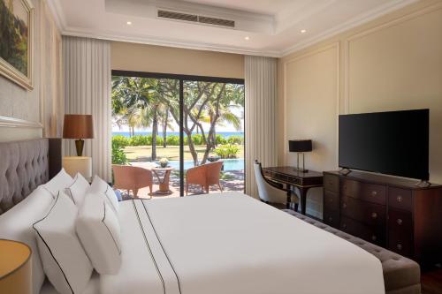 Meliá Vinpearl Cam Ranh Beach Resort في كام رنه: غرفة نوم بسرير كبير وتلفزيون
