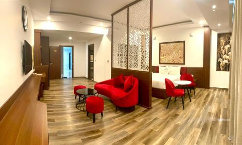 um quarto de hotel com um sofá vermelho e mesas e cadeiras em Levan Hotel em Phu Quoc