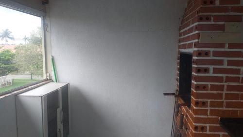 a room with a brick wall and a refrigerator and a window at Sobrado Guaratuba Central in Guaratuba