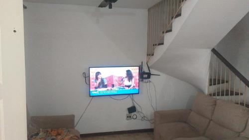 a living room with a tv hanging on a wall at Sobrado Guaratuba Central in Guaratuba