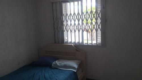 um pequeno quarto com uma cama e uma janela em Sobrado Guaratuba Central em Guaratuba