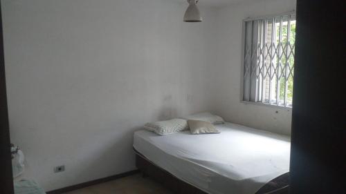 uma cama num quarto com uma janela em Sobrado Guaratuba Central em Guaratuba