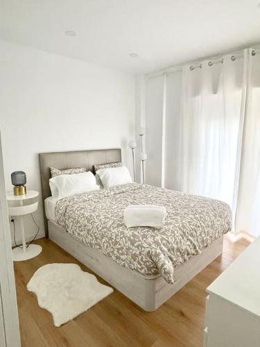 a white bedroom with a large bed with white pillows at Cosy Apartment - lovely stay/ Free parking/ Netflix in Falagueira