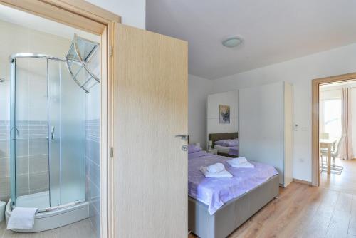 a bedroom with a bed and a glass shower at Apartments Medved in Vir