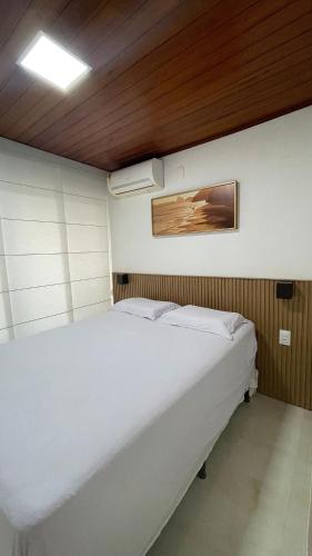 a white bed in a room with a wooden ceiling at Luxury Flat at Villa Hípica in Gravatá – PE | Locar House in Gravatá