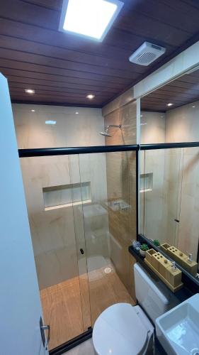 a bathroom with a toilet and a glass shower at Luxury Flat at Villa Hípica in Gravatá – PE | Locar House in Gravatá