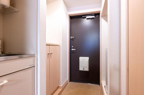 uma porta preta numa cozinha com um lavatório em Luana Hotel ベルビ早稲田 em Tóquio