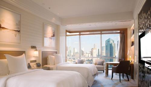 a hotel room with two beds and a large window at Four Seasons Hotel Tianjin in Tianjin