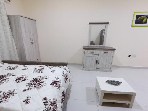 1 dormitorio con cama, mesa y espejo en استوديو مفروش, en Ajman