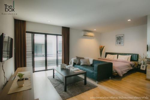 uma sala de estar com um sofá, uma cama e uma mesa em The Box Residence em Ban Lam Praya Phai Rua