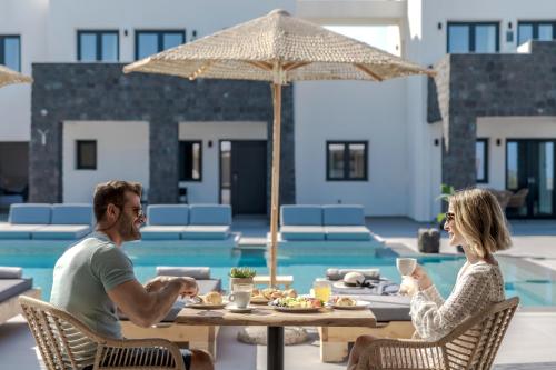 un homme et une femme assis à une table devant une piscine dans l'établissement Onyx Hotel & Suites, à Karterados