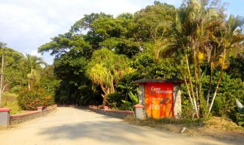 a dirt road with trees and a red building at Cabaña Eco-Arte in Tortugal