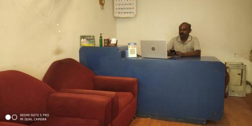 mężczyzna siedzący przy ladzie z laptopem w obiekcie Le Grace Bye Pass w mieście Maduraj
