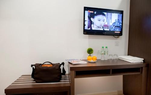 a room with a television on a wall with a bench at Big Orange Hotel Sungai Petani in Sungai Petani