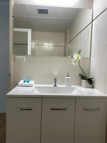 a bathroom with a white sink and a mirror at Oceania on Burleigh Beach in Gold Coast
