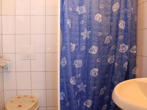 une salle de bain avec un rideau de douche bleu et des toilettes dans l'établissement Charmante maison oléronaise avec cour, proche plage et centre, 2 couchages, ménage inclus - FR-1-246A-371, à Dolus-d'Oléron