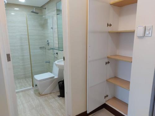 La salle de bains est pourvue de toilettes et d'une douche en verre. dans l'établissement Posh Beds with City View and Pools, à Manille