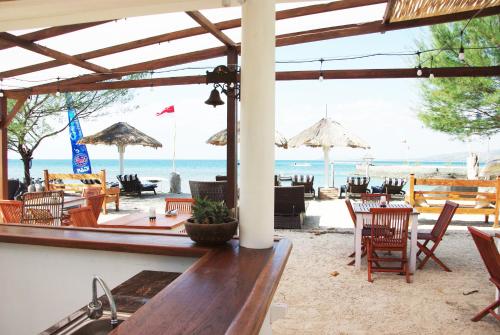 The High Dive Gili Gede by Ultimate Resorts في Gili Gede: مطعم على الشاطئ مع كراسي وطاولات