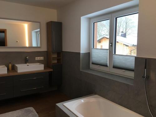 łazienka z wanną, umywalką i lustrem w obiekcie Ferienwohnungen Martlhof w mieście Leogang