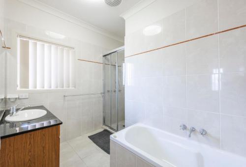 a white bathroom with a tub and a sink at Anchor Iluka in Iluka