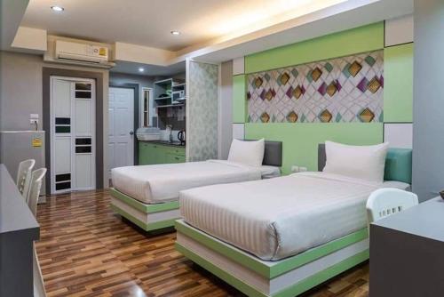 two beds in a room with green and white at The Ring Residence in Hat Yai