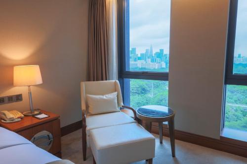 a hotel room with a chair and a window at Shenzhen Nanshan L'Hermitage in Shenzhen