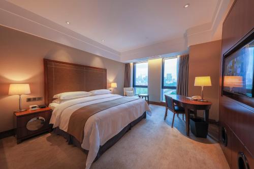 a hotel room with a large bed and a desk at Shenzhen Nanshan L'Hermitage in Shenzhen