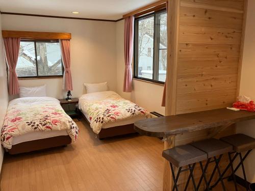 a room with two beds and a table and windows at Piremon in Hakuba