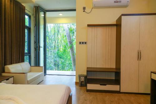 a bedroom with a bed and a cabinet and a window at Balishira Resort Ltd. in Sreemangal