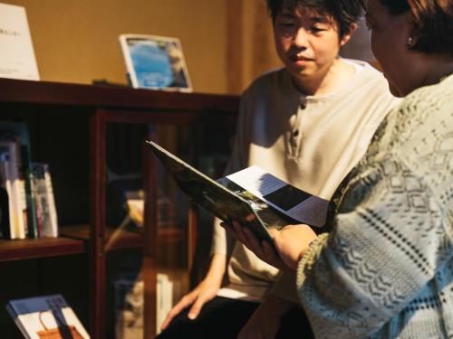 a woman reading a book while another woman looks at a book at Minamo in Ukiha