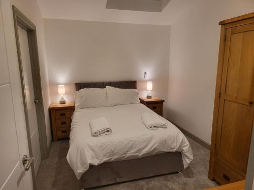 a bedroom with a bed and two night stands with lamps at Impeccable 1-Bed Apartment in Buxton Town Center in Buxton