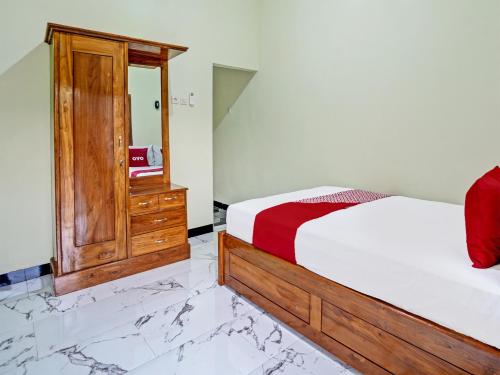 a bedroom with a bed and a cabinet and marble floors at OYO Life 92043 Kost Barokah Syariah Madiun in Madiun
