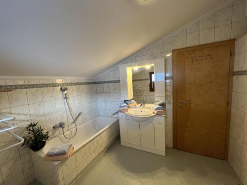 een badkamer met een bad, een wastafel en een douche bij Cozy apartment in Wald im Pinzgau with balcony and barbecue area in Wald im Pinzgau