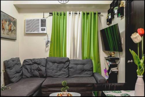 a living room with a couch and a green curtain at A Refreshing Condo Unit Near BGC, Ortigas & Makati with NETFLIX and WiFi in Manila