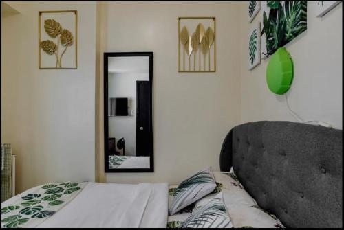 Schlafzimmer mit einem Bett und einem Wandspiegel in der Unterkunft A Refreshing Condo Unit Near BGC, Ortigas & Makati with NETFLIX and WiFi in Manila