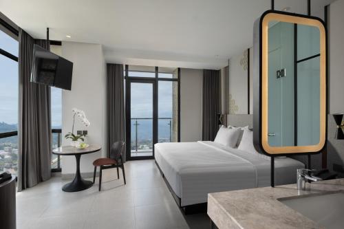 a hotel room with a bed and a table and a mirror at Hotel Santika Premiere Padang in Padang