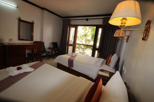 a hotel room with two beds and a window at Mom's Guesthouse in Siem Reap