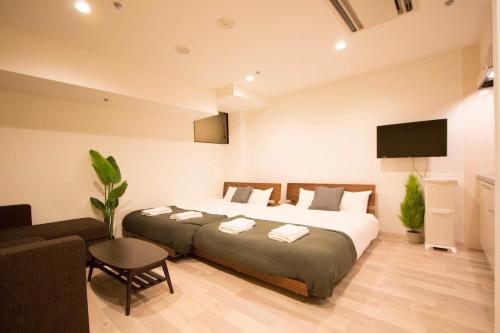 - une chambre avec 2 lits, une télévision et un canapé dans l'établissement SEVEN Building / Vacation STAY 4959, à Asahikawa
