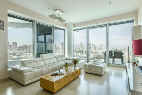 salon z białą kanapą i dużymi oknami w obiekcie Luxury 2 BR Apt w Pool & Panoramic View by Sea N' Rent w Tel Awiwie
