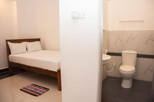 a small bathroom with a bed and a toilet at Sanmi Airport Resort in Katunayaka